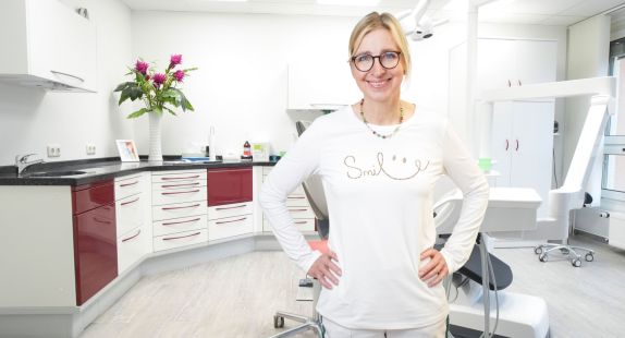 Dr. Kuntze lächelt im Behandlungsraum mit moderner Praxiseinrichtung.
